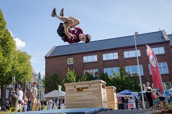 Ein Junge mache einen Sprung mit Drehung in der Luft