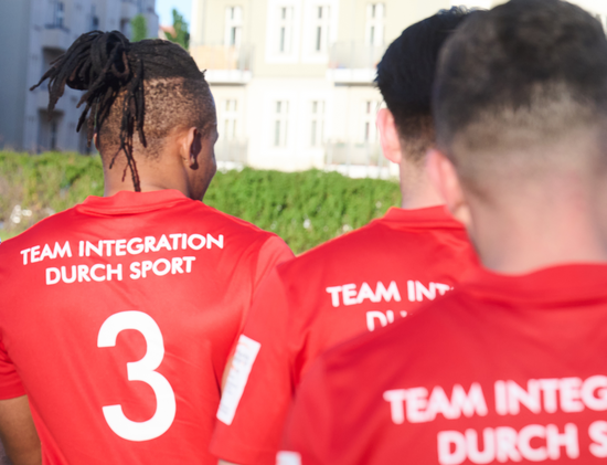 Männer tragen Spielertrikots mit der Aufschrift: Team Integration durch Sport